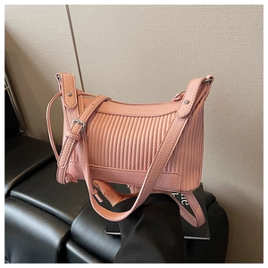 Detail of pink shoulder bag featuring vertical pleated texture and silver hardware accents