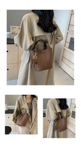 Detail view of brown lychee grain leather bucket bag with elegant leaf pendant charm