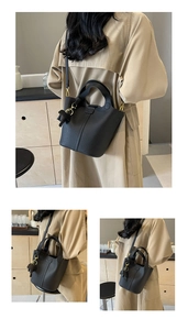 Detailed view of black lychee grain leather bucket bag with cute bear charm and gold hardware
