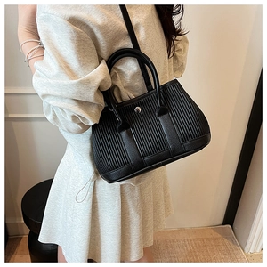 Detail of black pleated leather tote bag showing texture and circular metallic snap button