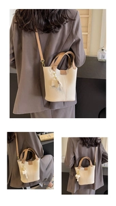 Detail of lychee pattern bucket bag featuring dual handles and elephant pendant charm