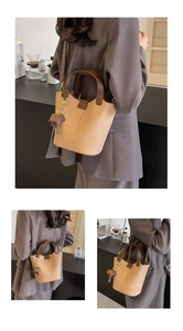 Detail view of khaki bucket bag with lychee leather texture and cute elephant charm
