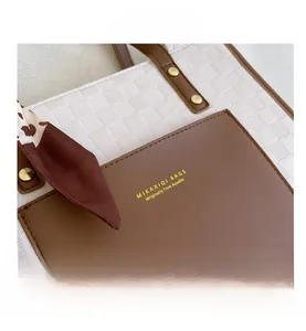 Detail of white checkered tote bag with brown leather pocket and decorative floral scarf