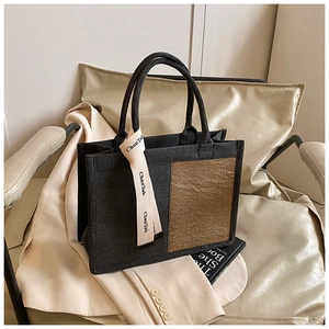 Detail of felt tote bag with brown panels and beige ribbon on an armchair