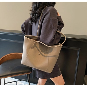 Detail of the litchi texture leather tote bag with a small front pocket and button detail
