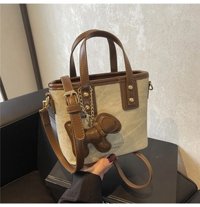 Close-up of canvas bucket bag with brown leather trim and cute puppy charm detail