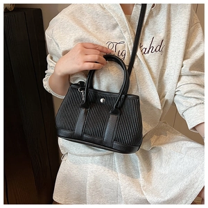 Detailed shot of a black vertical pleated bucket bag with silver snap button closure