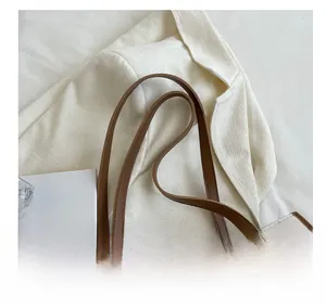 Detail of cream tote bag with checkered texture, brown straps, and decorative silk scarf