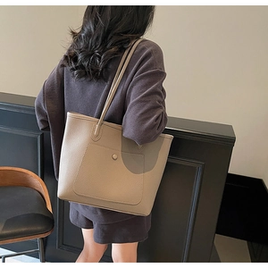 Detail of minimalist beige pebble leather tote bag with functional front snap pocket