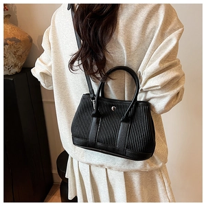 Detail of black pleated leather handbag with silver clasp on a stylish shoulder strap