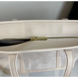 Close-up of the smooth golden metal zipper and marble pattern detail on the tote bag