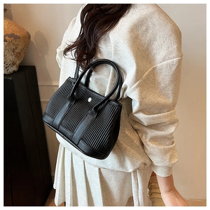 Detail of black leather bucket bag with unique vertical pleated texture and silver buckle