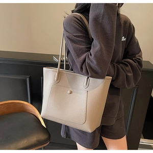 Detail of grey lychee leather tote bag with round buckle pocket for daily commute