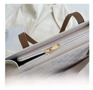 Detail of golden metal zipper and woven checkerboard texture on a white tote bag