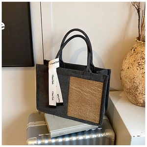 Detail of charcoal canvas tote bag featuring khaki patch and ribbon handle accent