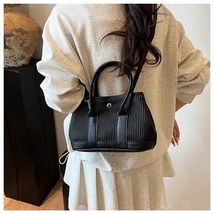 Detail of black pleated bucket bag featuring lychee texture leather and silver buckle