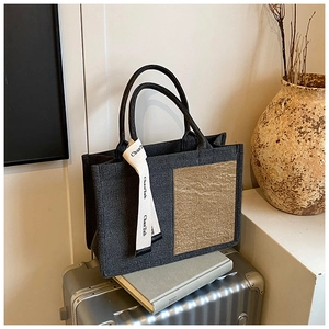 Detailed close-up of dark grey canvas tote bag with khaki textured panel and logo strap