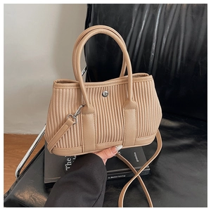Detail of beige pleated bucket bag featuring vertical texture and circular metal buckle