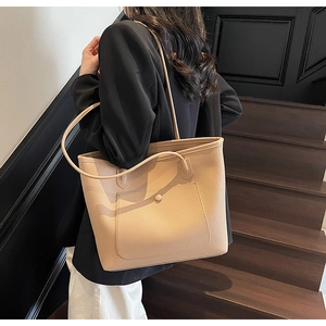Detail of beige pebble leather tote bag featuring a front pocket and long shoulder straps