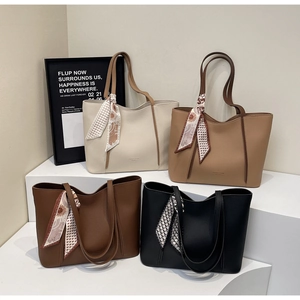 Detail of four large leather tote bags with silk scarves on tiered modern display