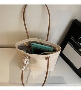Detail shot of large cream tote bag showing spacious interior with phone and tablet