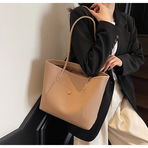 Close-up of beige pebble grain leather tote bag with functional front snap pocket