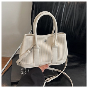 Detailed close-up of cream pleated bucket bag with vertical embossed texture and metal button