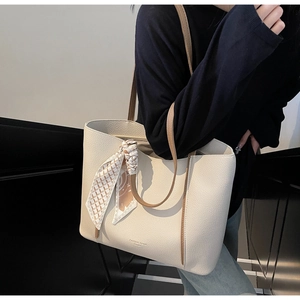 Off-white lychee grain tote bag with silk scarf accent worn by a model in modern setting