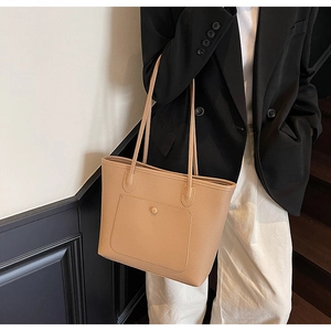 Detail view of khaki lychee leather tote bag with front pocket shown on shoulder