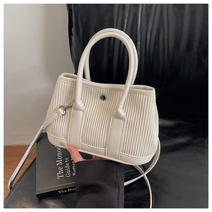 Detailed macro shot of creamy white pleated bucket bag with silver metal ring and handle