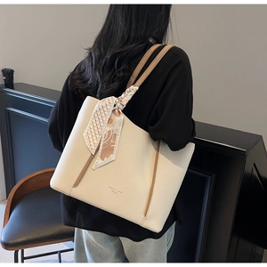Detail of a beige leather tote bag with floral silk scarf wrap and brown trim