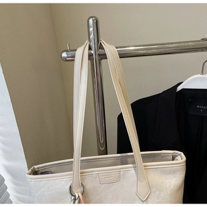 Detail showing beige pebbled leather tote bag with FASHION & BAGS logo embossing