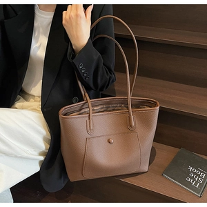 Detail of brown litchi pattern leather tote bag with buckle pocket and striped lining