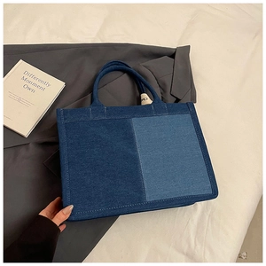 Detailed view of bicolor denim tote bag featuring dual-tone blue panels and inner lining
