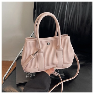 Detail of pink pleated bucket bag showing textured vertical ribs and metallic buckle