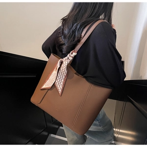 Detail of caramel brown lychee leather tote bag with stylish patterned silk scarf on handle