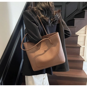 Detailed view of brown lychee grain leather tote bag with magnetic front pocket on a model
