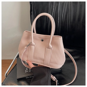 Detailed close-up of light pink pleated bucket bag with silver snap button on black chair