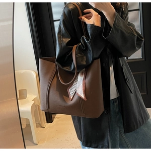 Detail view of large brown pebbled leather tote bag with a decorative silk scarf