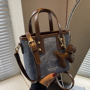 Retro denim bucket bag with brown leather trim and cute puppy charm on a mini tote