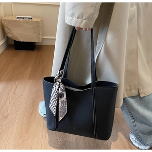 Close-up of black leather tote bag with lychee texture and decorative silk scarf