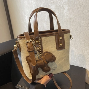Chic canvas and brown leather bucket bag with puppy charm and adjustable strap