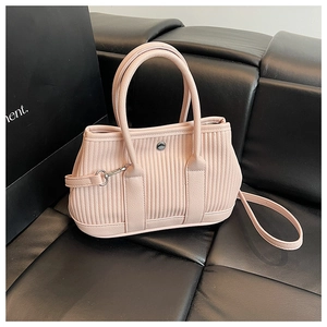Detail of pink pleated leather bucket bag featuring round metal clasp and detachable strap
