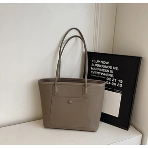 Detailed close-up of taupe tote bag with pebble texture and front pocket design