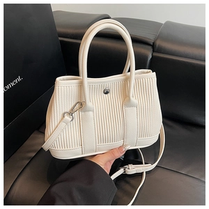 Detailed texture of beige pleated bucket bag with vertical embossed pattern and metal snap