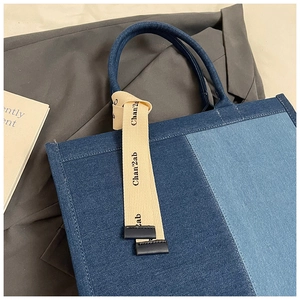 Detail of blue patchwork denim tote bag with decorative printed ribbon and texture