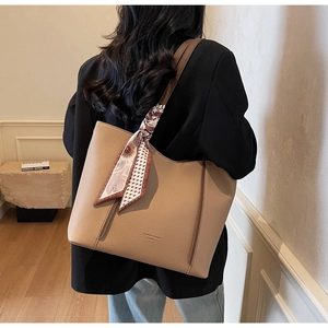 Detail of khaki tote bag featuring pebble grain leather and decorative floral silk scarf