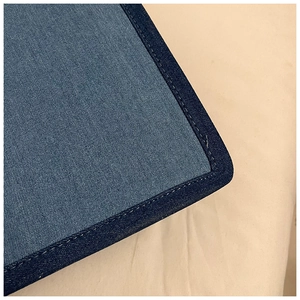 Detailed view of the double-stitched edges on the blue denim tote bag with fine textures