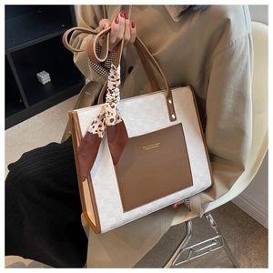 Detail of white checkered tote bag with brown leather pocket and chic cow print scarf