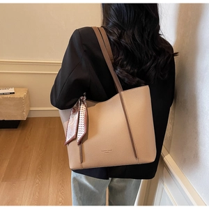 Detailed view of beige pebble leather tote bag with silk scarf on a female model